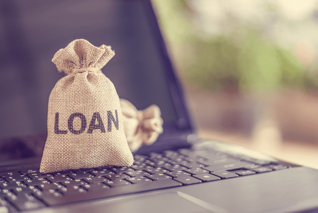 This is a picture of a fabric bag with the word “Loan” written on it. The bag is on top of a laptop’s keyboard. Our hard money lenders in Massachusetts offer secure loans and financing.